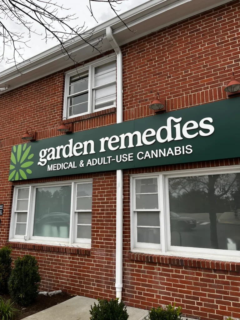 Garden Remedies sign on a red-brick Newton storefront, with white-trimmed windows and green lettering.