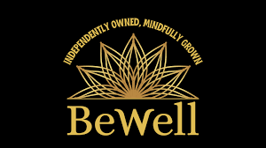 BeWell logo: gold lotus-like emblem above the word BeWell in gold, on black background, with the curved slogan 'Independently Owned, Mindfully Grown' around the emblem.